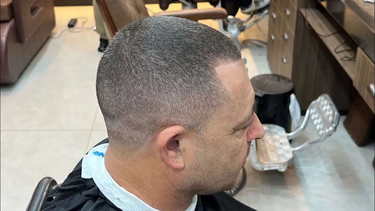 Barbeiro fazendo corte com técnica de degradê