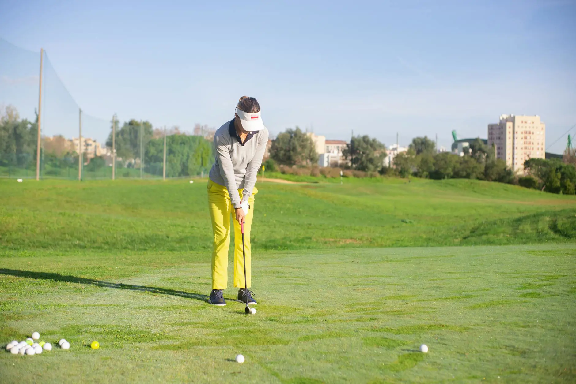 Woman golfer focusing on her putt at a sunny Portuguese golf course.