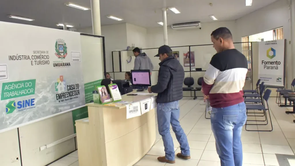 Recepcionista em hotel atendendo hóspede no balcão de um meio de hospedagem no Paraná